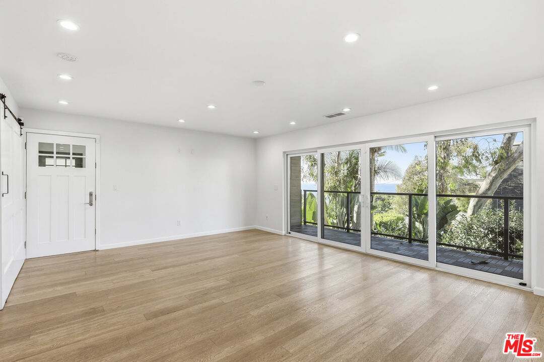 2442 South Coast Highway, Unit 4 Laguna Beach, CA 92651 - Photo 5 of 22 a view of an empty room with wooden floor and a window