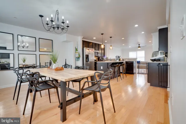 a kitchen with stainless steel appliances granite countertop a stove top oven a sink a dining table and chairs with wooden floor