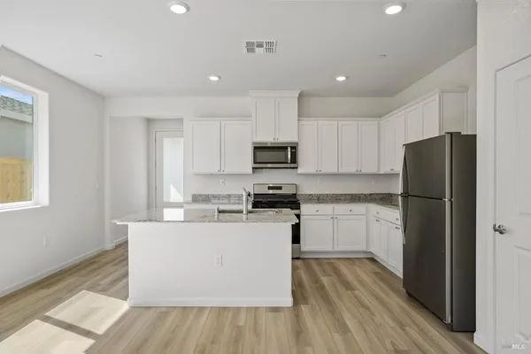 a kitchen with a refrigerator a stove top oven and wooden floors