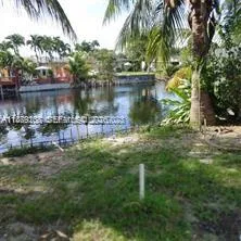 a backyard of a house with lawn chairs plants and lake view
