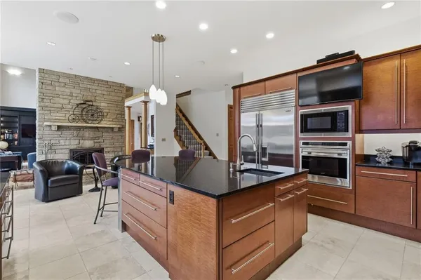 a kitchen with stainless steel appliances granite countertop a sink a stove and a wooden cabinets