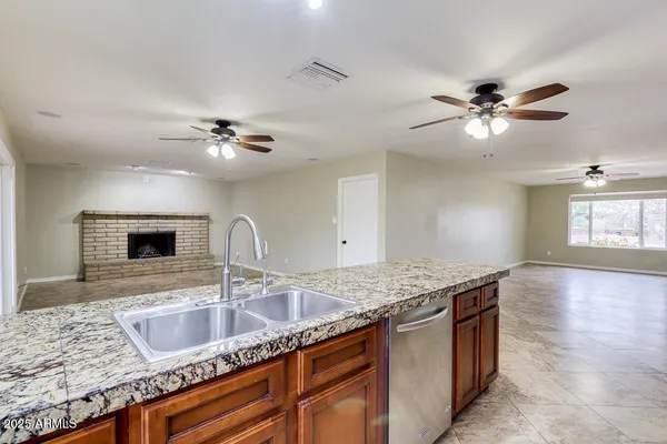 a kitchen with granite countertop a sink a counter top space and cabinets