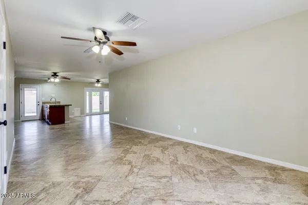an empty room with wooden floor chandelier fan and windows