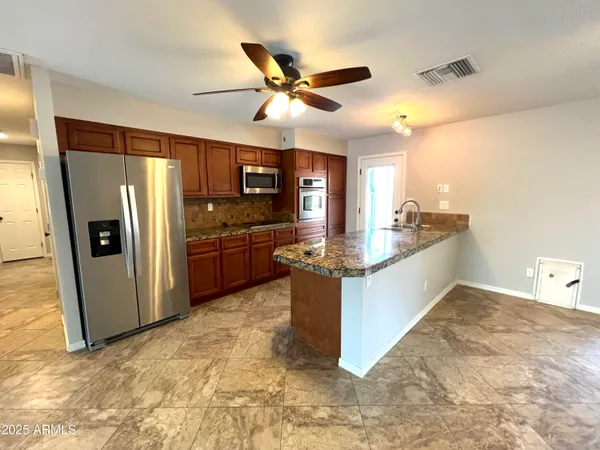 a kitchen with stainless steel appliances kitchen island granite countertop a refrigerator and a sink