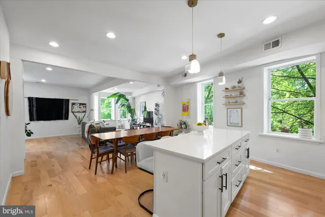 a kitchen with a stove a refrigerator a sink dishwasher with a dining table and chairs with wooden floor