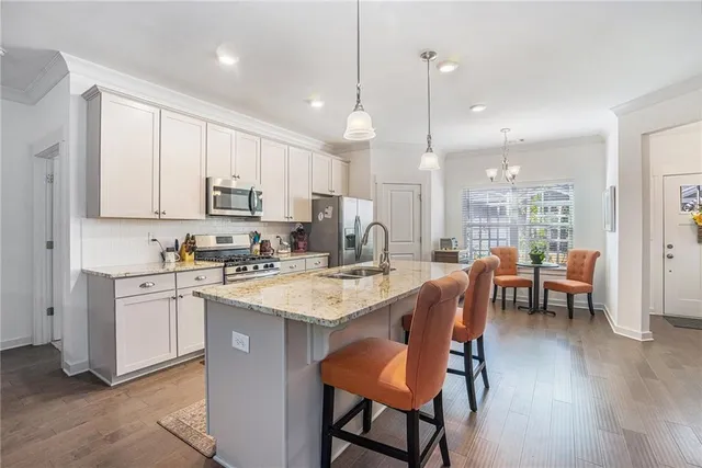 a kitchen with stainless steel appliances granite countertop a table chairs sink refrigerator and cabinets