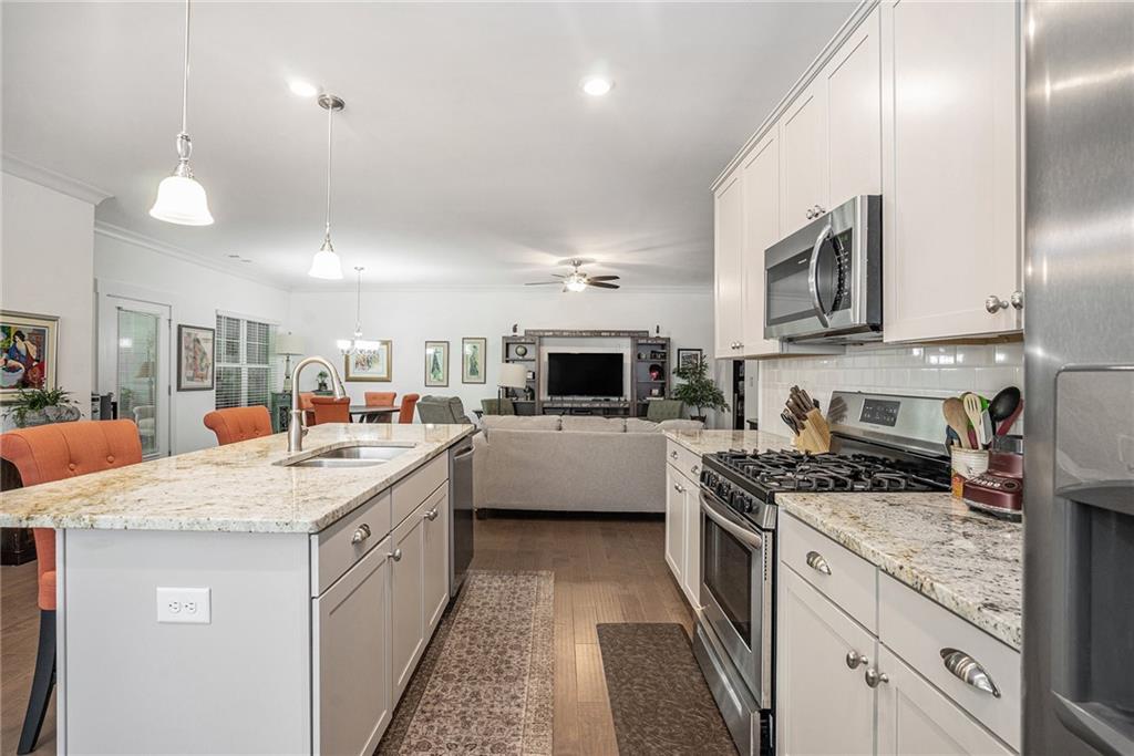 2473 Rathburn Circle Loganville, GA 30052 - Photo 15 of 32 a kitchen with stainless steel appliances kitchen island granite countertop a stove top oven a sink a counter space and cabinets