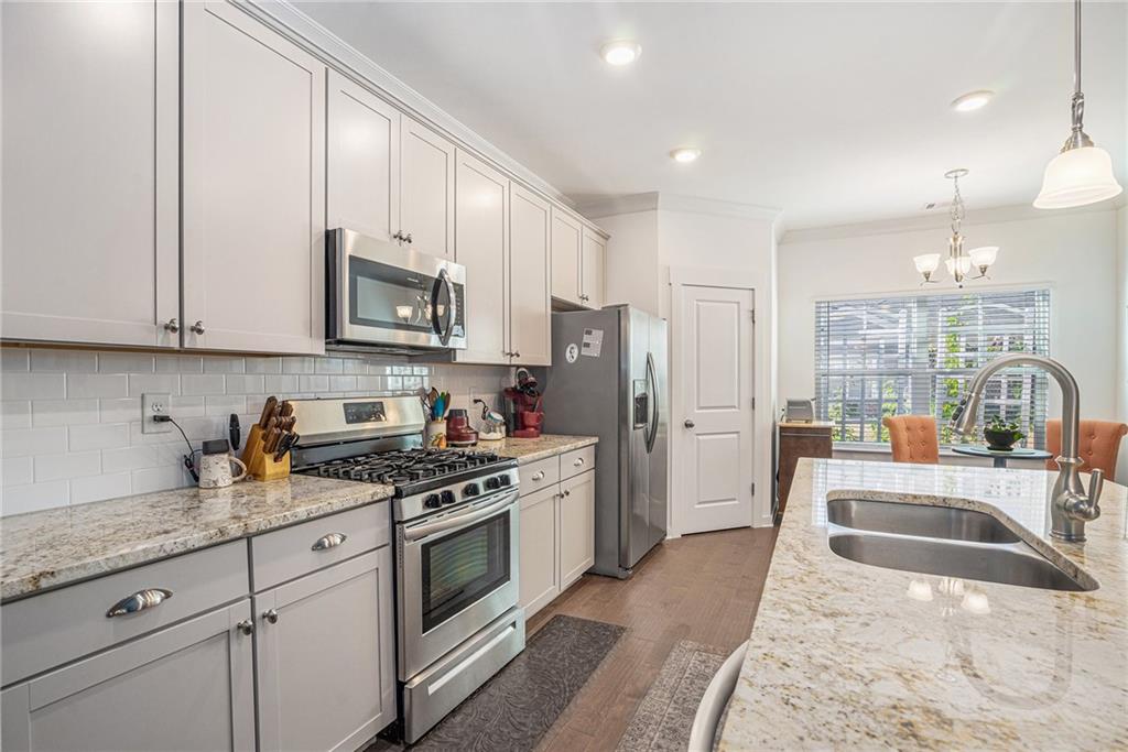 2473 Rathburn Circle Loganville, GA 30052 - Photo 16 of 32 a kitchen with stainless steel appliances granite countertop a stove a refrigerator a sink a oven with white cabinets and wooden floor