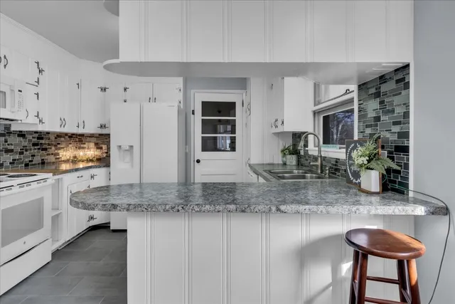 a kitchen with stainless steel appliances granite countertop a sink stove and white cabinets