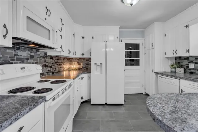 a kitchen with granite countertop a sink a stove and refrigerator