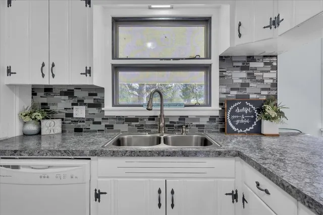 a kitchen with granite countertop a sink a stove and cabinets