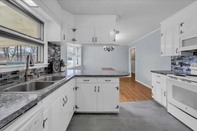 a kitchen with granite countertop white cabinets white stainless steel appliances and sink
