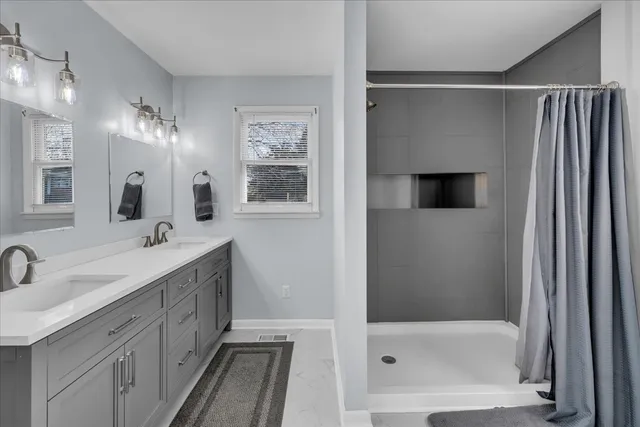 a bathroom with a double vanity sink a large mirror and shower