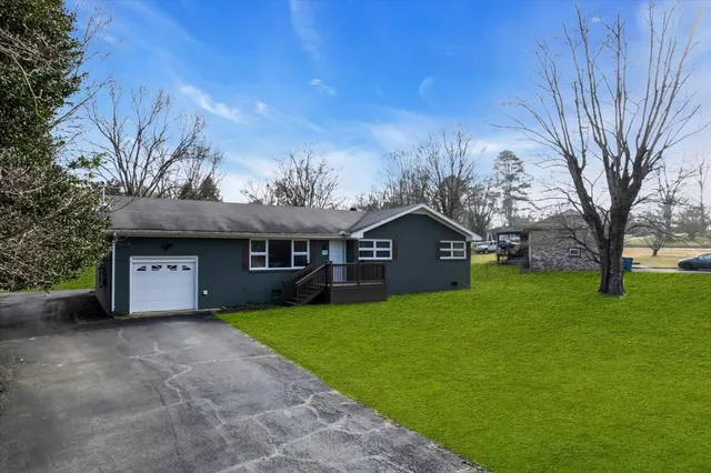 a view of a house with a big yard and large tree