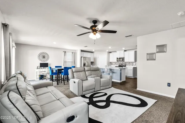 a living room with furniture a chandelier fan and a rug