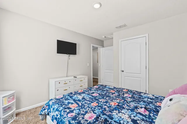a bedroom with a bed and a flat tv screen on the dresser