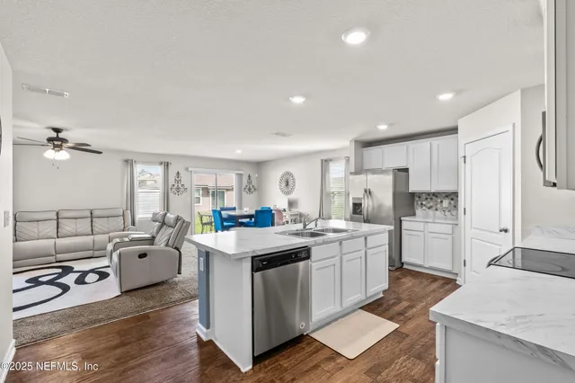 a kitchen that has a lot of white cabinets and stainless steel appliances