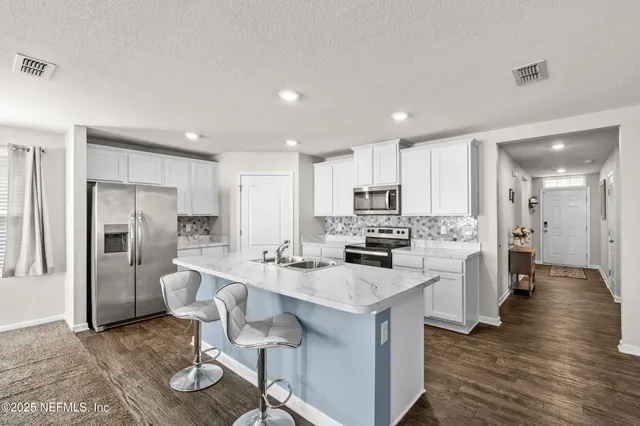 a kitchen with refrigerator and chairs