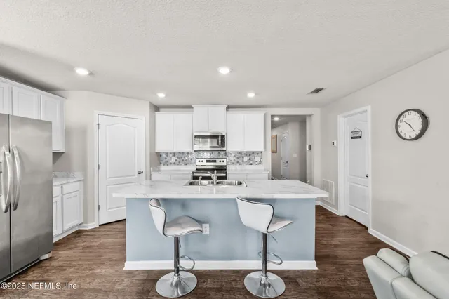 a kitchen with stainless steel appliances kitchen island granite countertop a dining table chairs and granite counter tops