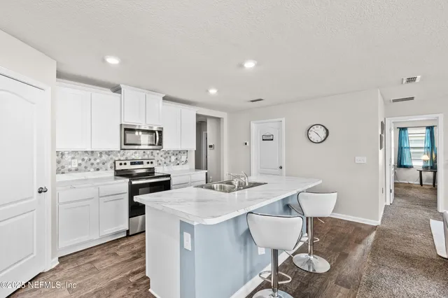 a kitchen with a sink a stove and white cabinets