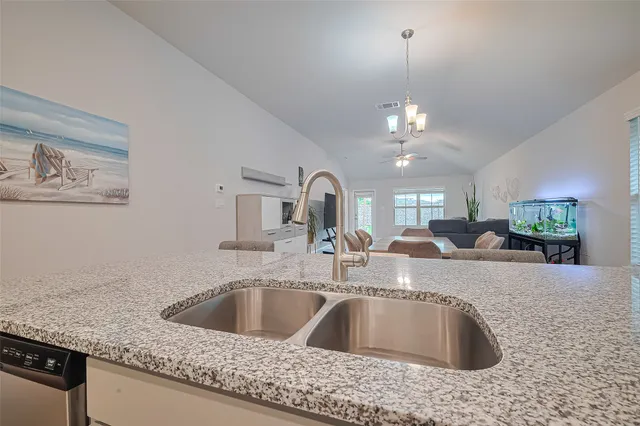 a kitchen with a sink granite counter tops and a view of living room