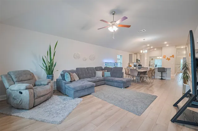 a living room with furniture and a dining table with wooden floor
