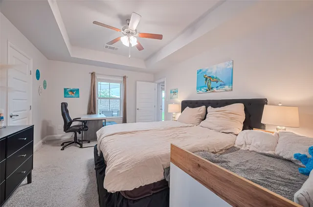 a bedroom with a bed a computer on the desk and a dresser