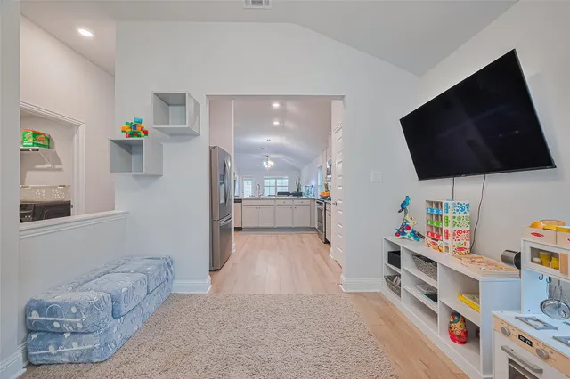 a view of an entryway with wooden floor and a flat screen tv