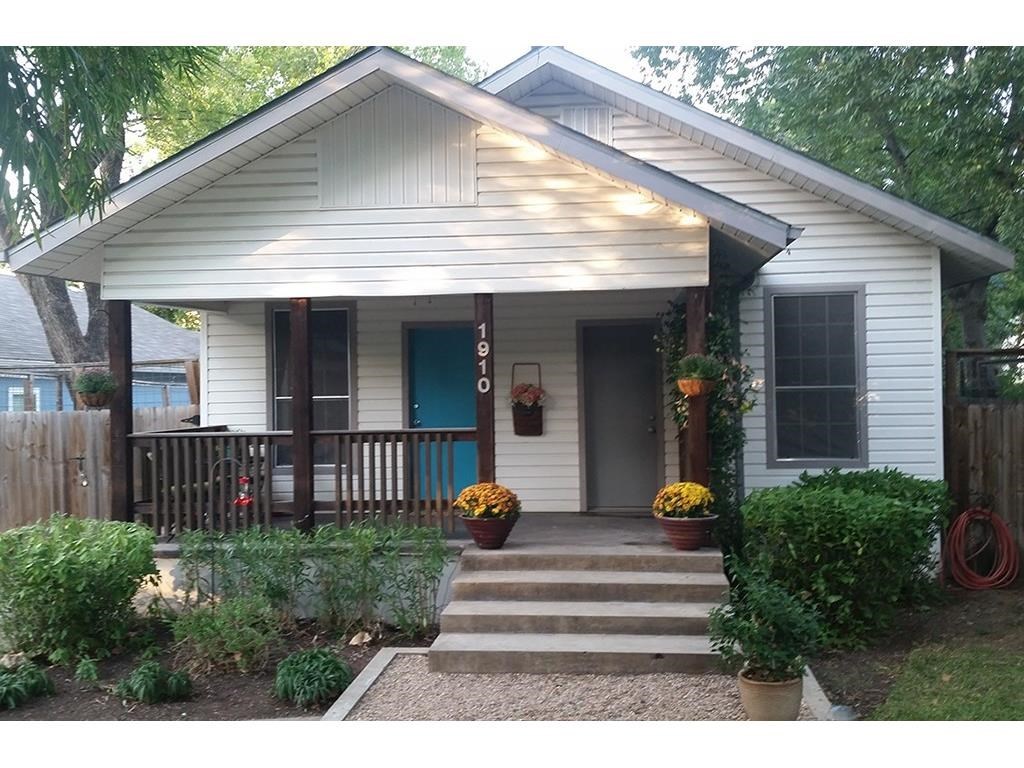 a view of a house with a small yard plants and large tree