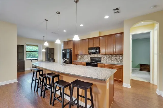 a large kitchen with stainless steel appliances granite countertop a stove a sink and a refrigerator