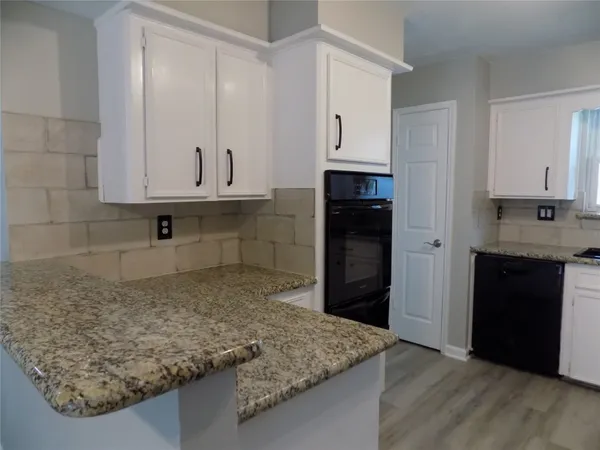 a kitchen with kitchen island granite countertop white cabinets and refrigerator