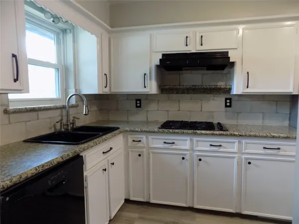 a kitchen with granite countertop white cabinets and black appliances