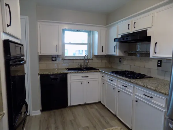 a kitchen with granite countertop cabinets stainless steel appliances a sink and a window