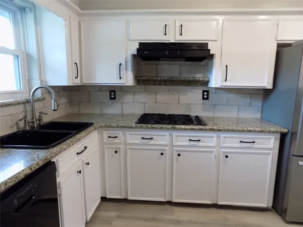 a kitchen with stainless steel appliances granite countertop white cabinets a stove a sink and dishwasher