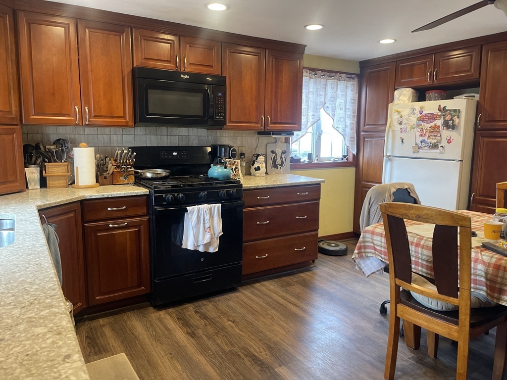 70 Wheaton Avenue Rehoboth, MA 02769 - Photo 12 of 42 a kitchen with stainless steel appliances granite countertop a stove top oven a refrigerator and a dining table with wooden floor