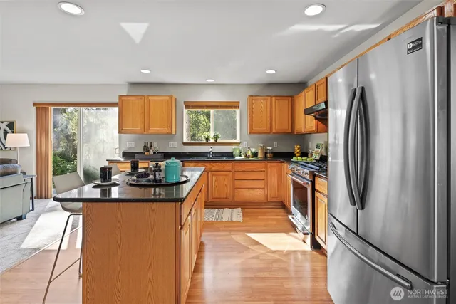 a kitchen with stainless steel appliances granite countertop a refrigerator a sink a stove and island