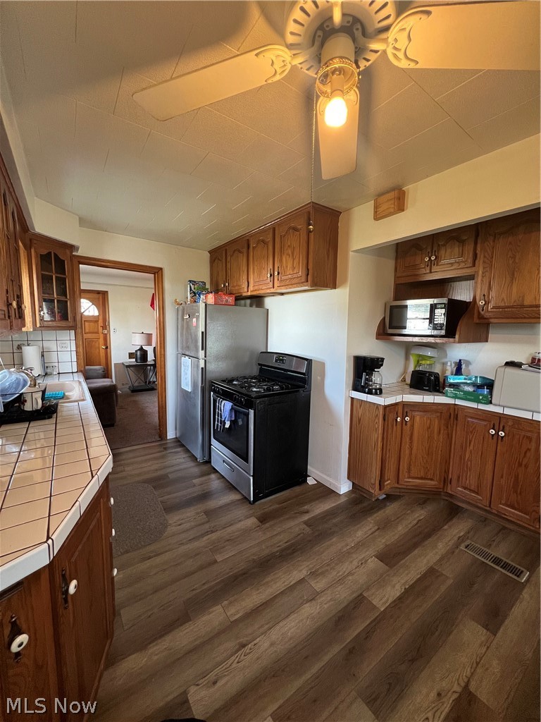 3892 East 189th Street Cleveland, OH 44122 - Photo 2 of 16 Kitchen featuring dark hardwood / wood-style flooring, tasteful backsplash, ceiling fan, gas range oven, and tile countertops