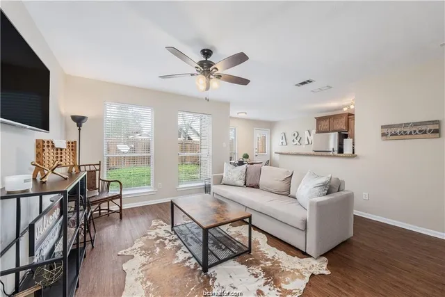 a living room with furniture a flat screen tv and a large window