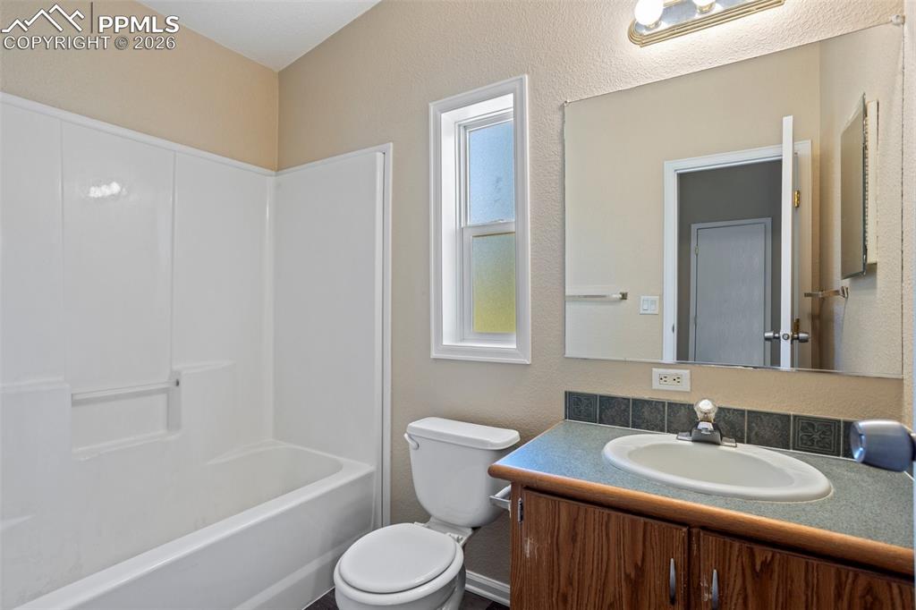7765 Valley Quail Point Colorado Springs, CO 80922 - Photo 29 of 37 a bathroom with a sink a toilet a mirror a bathtub and shower