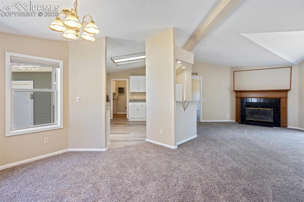 7765 Valley Quail Point Colorado Springs, CO 80922 - Photo 7 of 37 an empty room with a fireplace and a chandelier