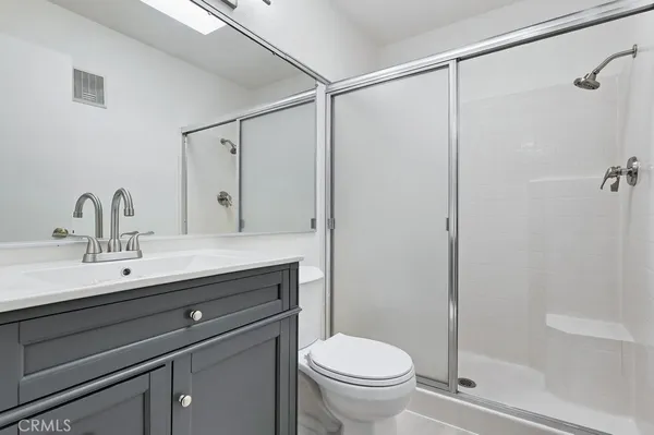 a bathroom with a sink a toilet a mirror and shower