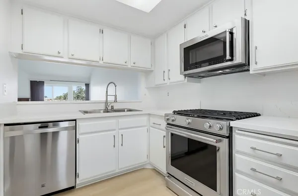 a kitchen with white cabinets and appliances
