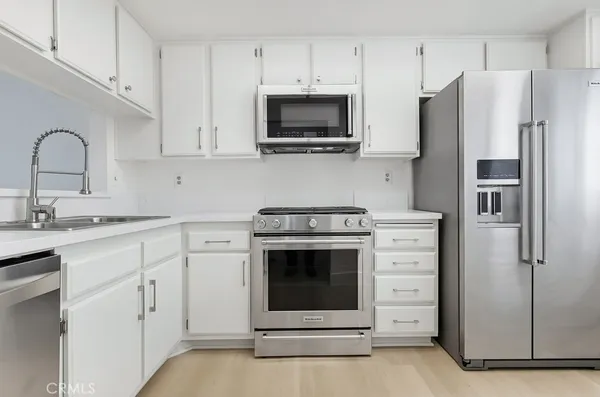 a kitchen with white cabinets and stainless steel appliances
