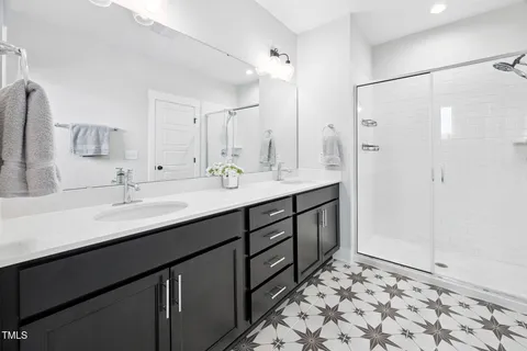 a bathroom with a double vanity sink mirror and shower