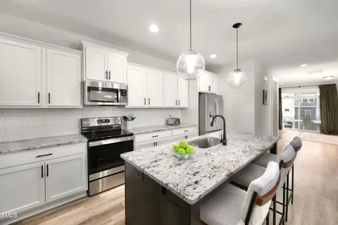 a kitchen with kitchen island granite countertop a sink a stove a microwave a center island and cabinets