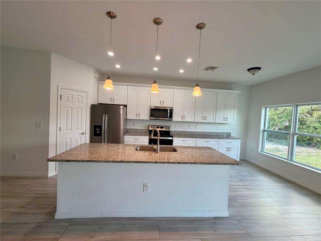 14142 Appleton Boulevard Port Charlotte, FL 33981 - Photo 5 of 26 a large kitchen with kitchen island a large counter space a sink appliances and cabinets