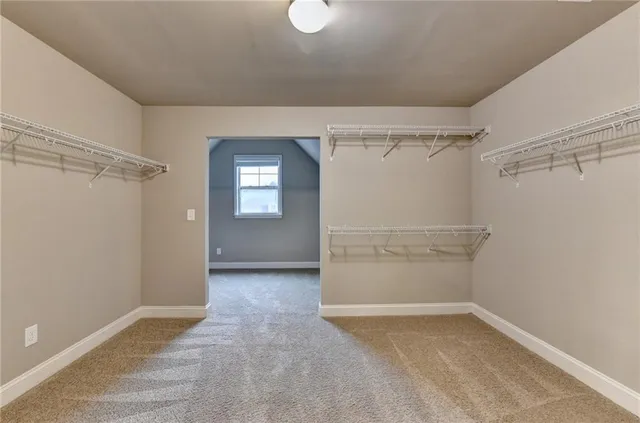 an empty room with chandelier fan and window