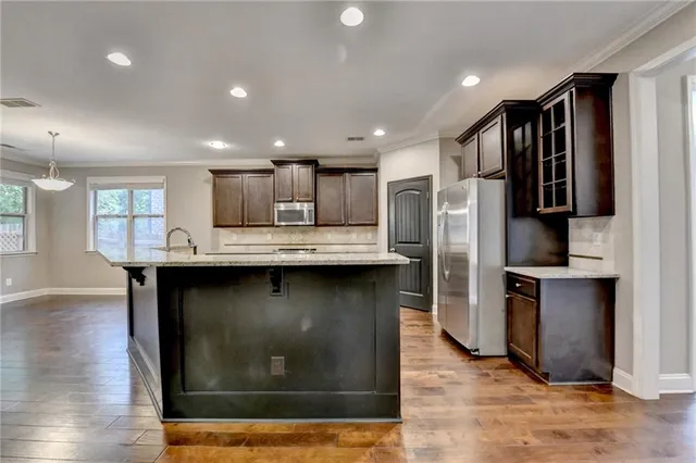 a kitchen with stainless steel appliances granite countertop a stove a sink and a refrigerator with wooden floor