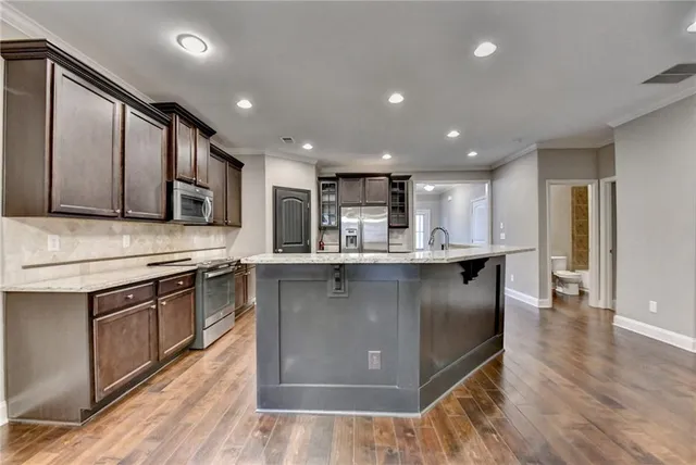 a kitchen with stainless steel appliances kitchen island granite countertop a refrigerator and a sink