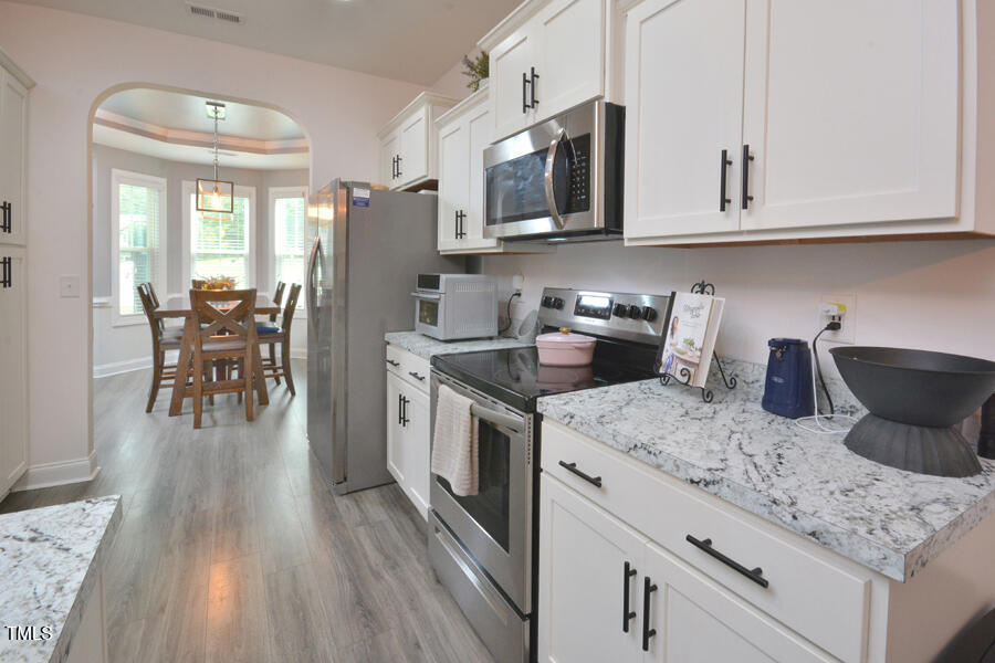 195 Timberwind Road Franklinton, NC 27525 - Photo 12 of 28 a kitchen with stainless steel appliances granite countertop a stove top oven a sink dishwasher a dining table and chairs with wooden floor